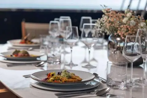 Olimp yacht table set with white napkins, china, glasses and plated dish