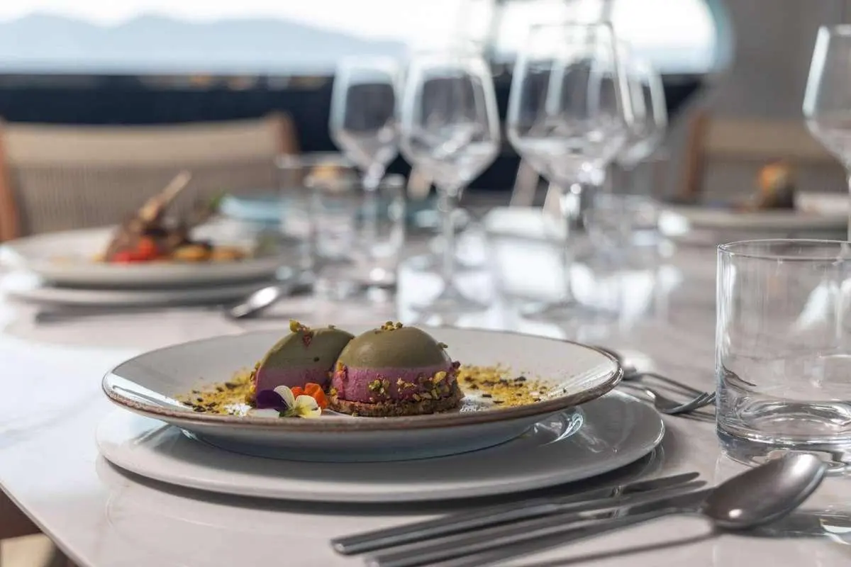 Olimp yacht table setting with plated dish and wine glasses on deck