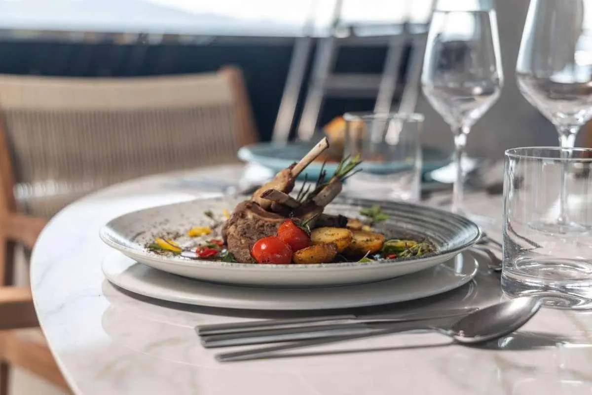 Olimp yacht table setting with plated dish and wine glasses on deck