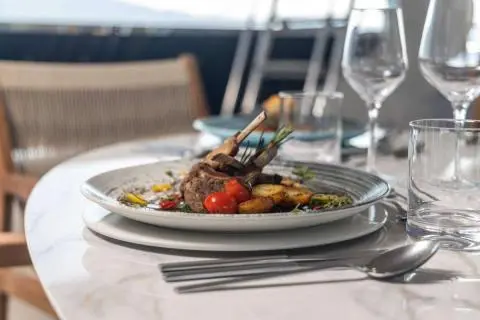 Olimp yacht table setting with plated dish and wine glasses on deck