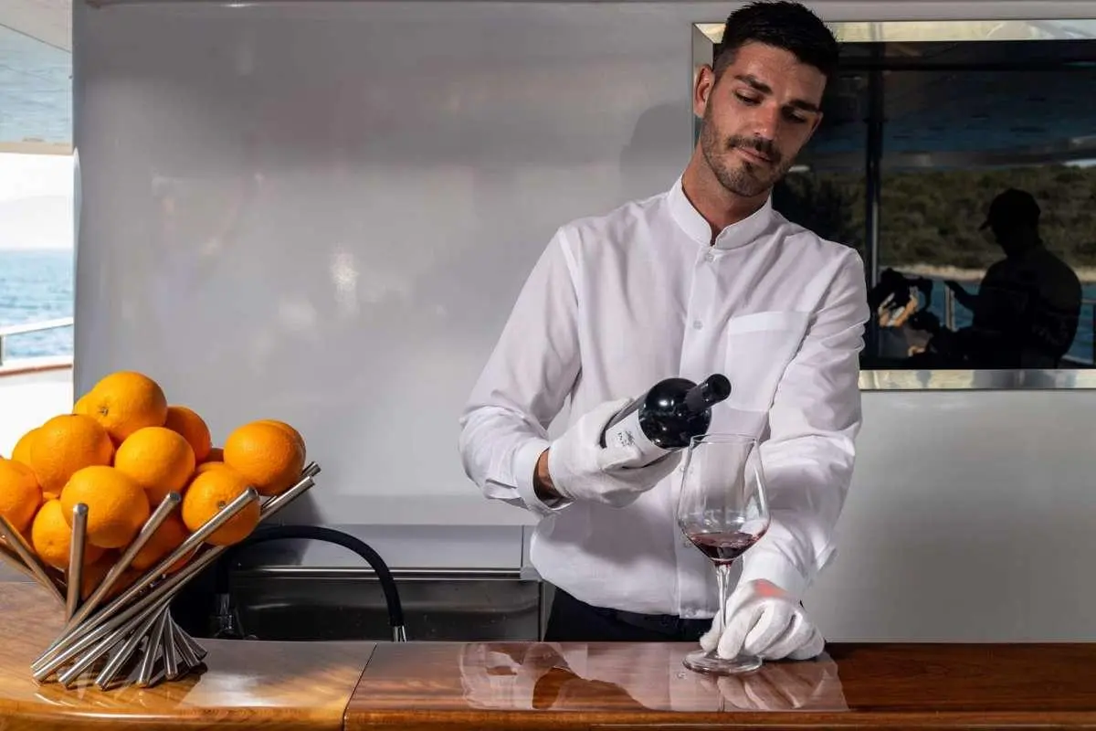 Chef in white jacket filming a live demo in a yacht galley with oranges nearby