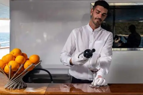 Chef in white jacket filming a live demo in a yacht galley with oranges nearby