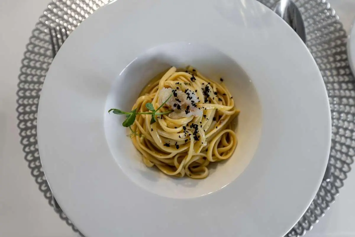 Close-up of a plate of pasta with herbs on a white table aboard Cristal yacht