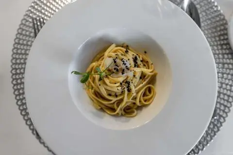 Close-up of a plate of pasta with herbs on a white table aboard Cristal yacht