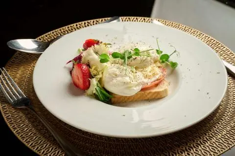 Close-up plate with sliced pastry, berries, edible flowers on white plate