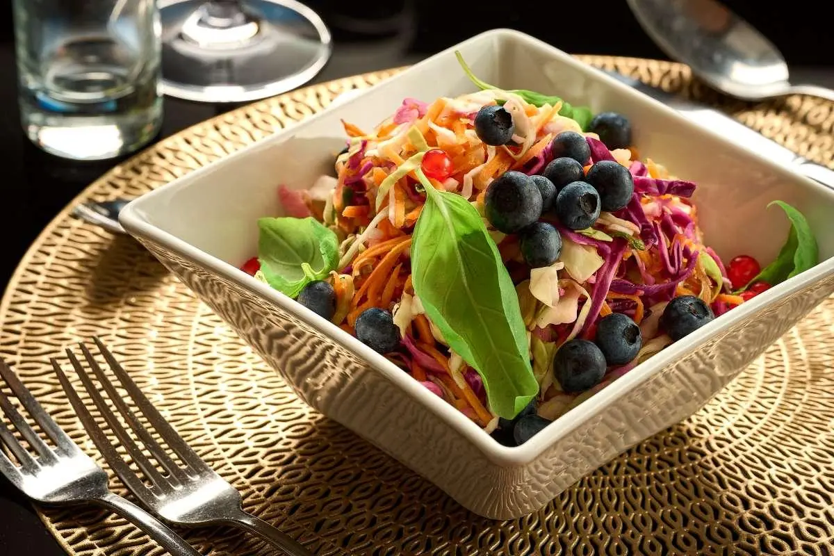Queen Eleganza yacht deck dining scene with colorful salad bowls near water