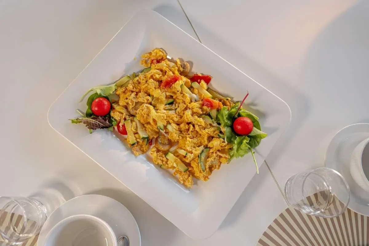Top-down view of a golden fried rice dish served in a clear container on a yacht table