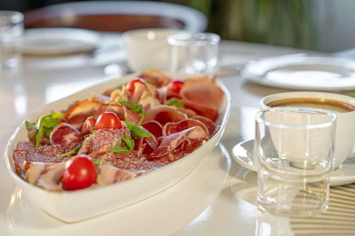 Close-up of a fruit-topped salad positioned on a yacht deck table with cups nearby