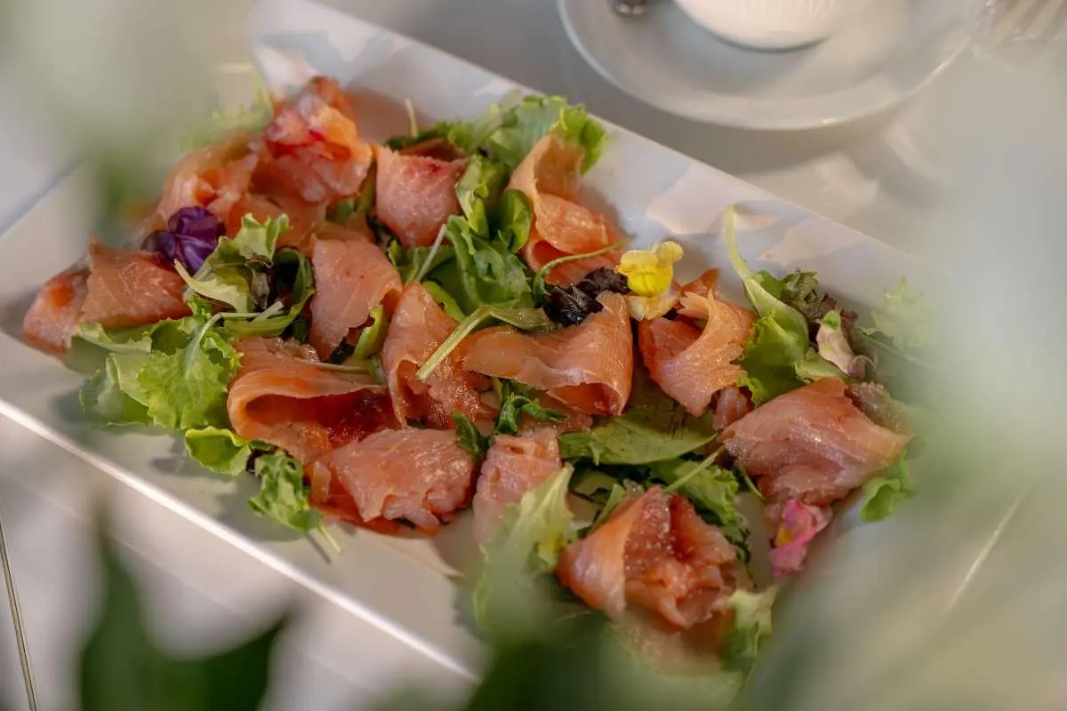 Smoked salmon carpaccio on a bed of mixed greens with delicate edible flowers