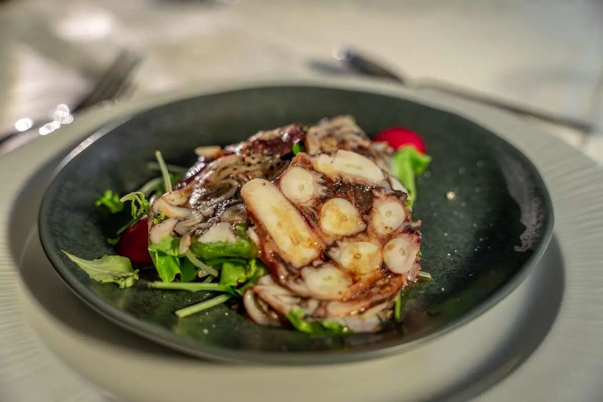 Karizma yacht menu dish presented in a dark bowl with greens and almonds