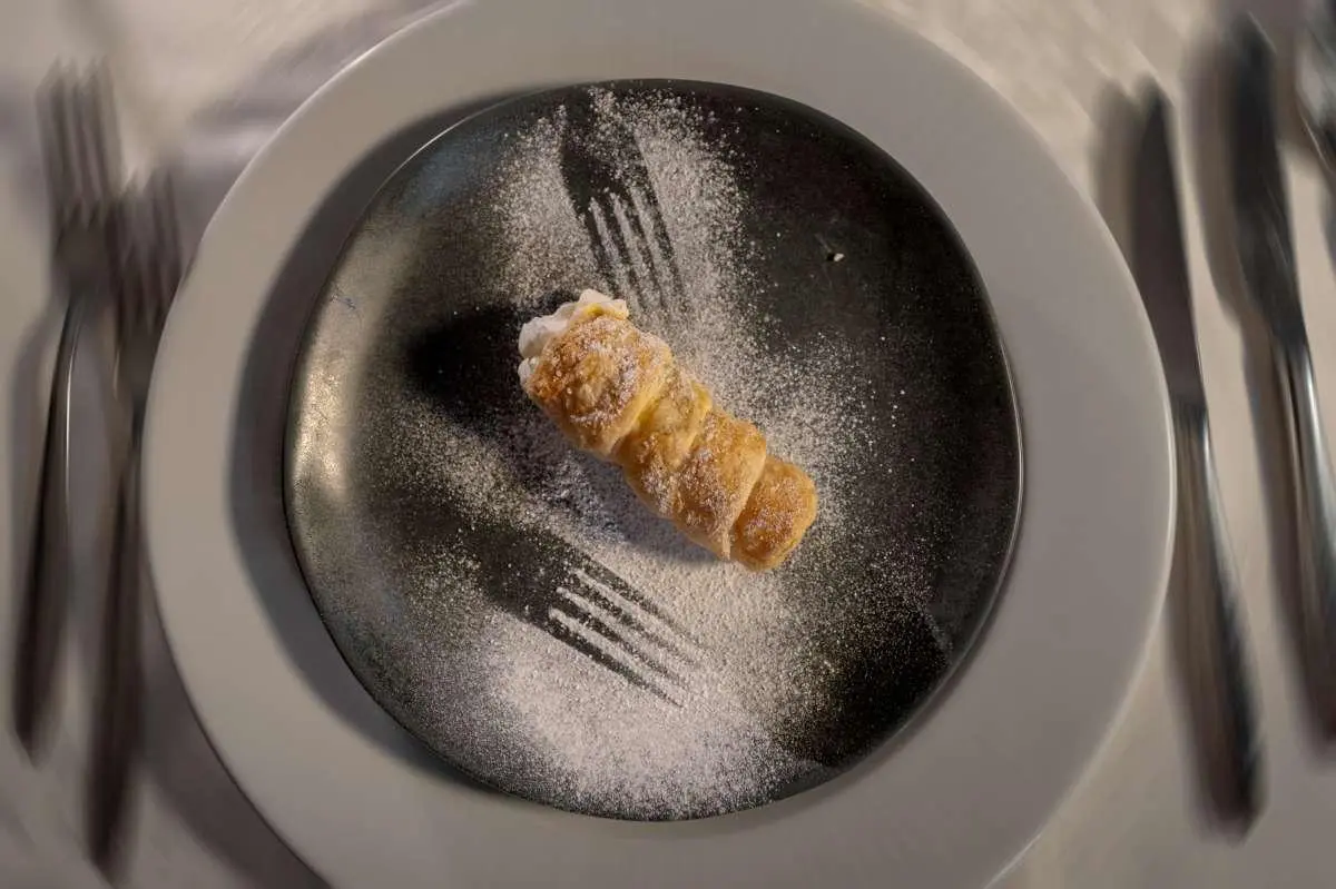 Close-up of a lobster-like dish on a dark pan, overwhelmed by shadows
