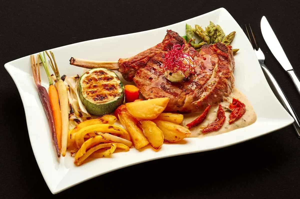 Luna yacht menu plate with steak, fries, greens and sauce on white