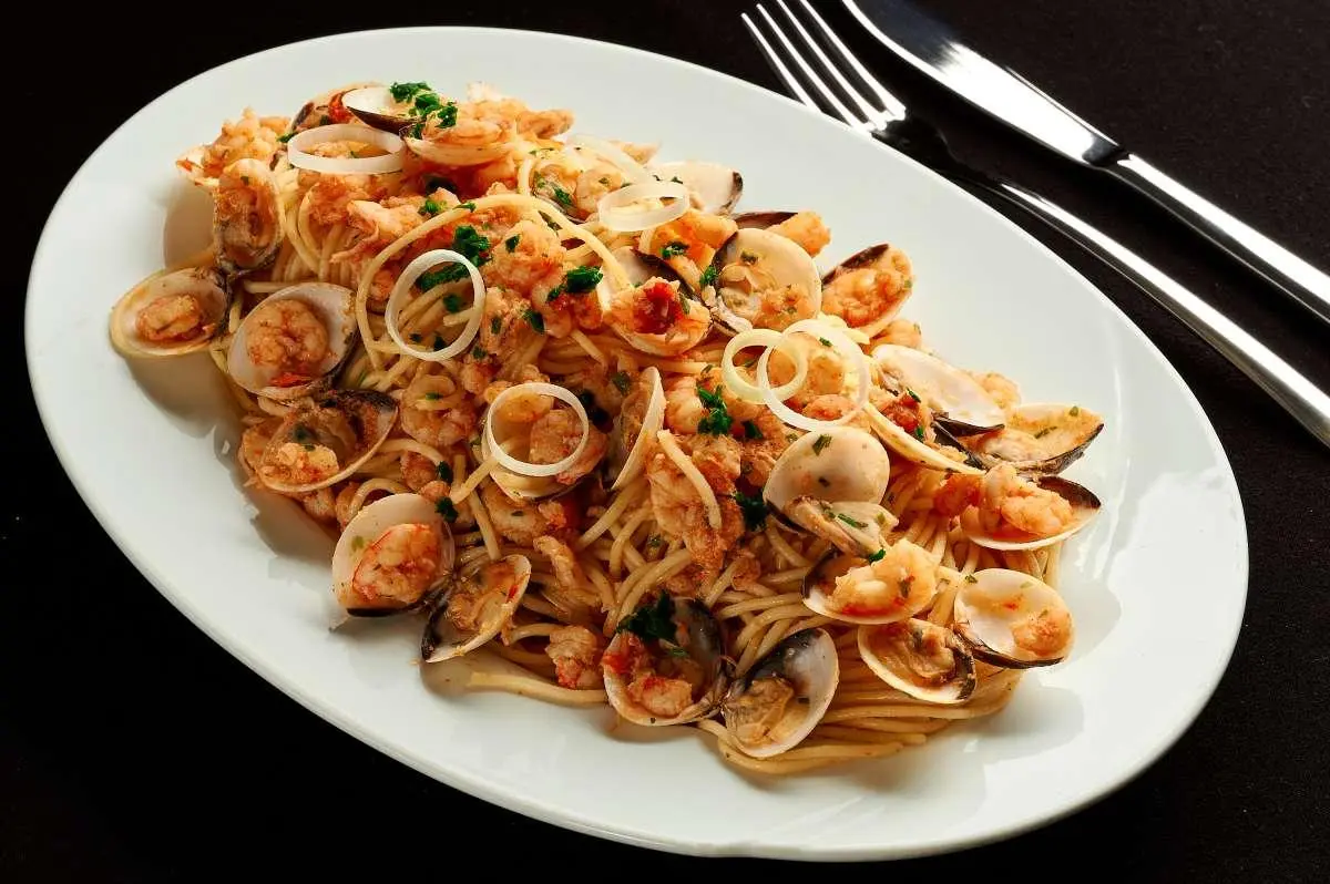 Luna yacht menu dish on plate with pasta and craned clams on table