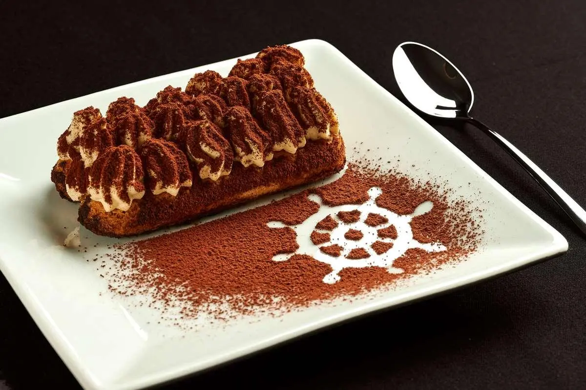 Close-up of dessert plate with chocolate cake and cocoa art on a white tray