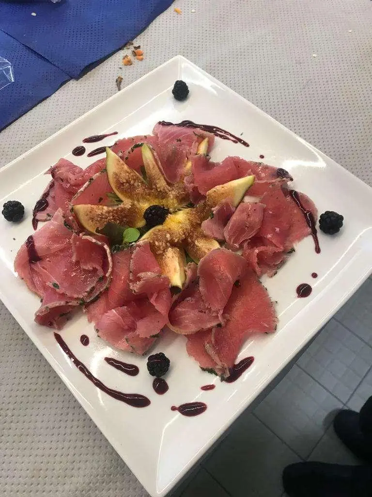 Plate with sliced red meat and sauce dots on a white square dish aboard a yacht