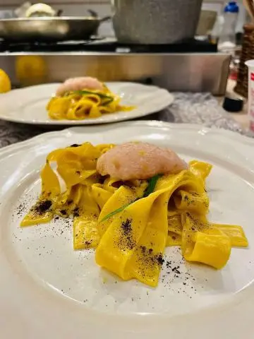Genny yacht scene with plated pasta pasta dish and lemon wedges on table