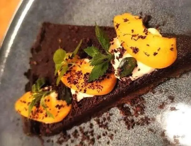 Cartouche yacht sample menu dish served on wooden board with yellow petals
