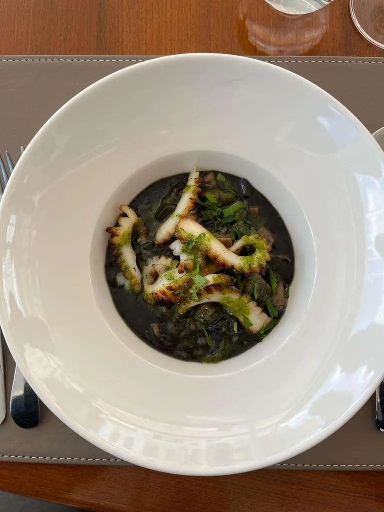 Overhead view of a small dish with green herbs in a white bowl on a table