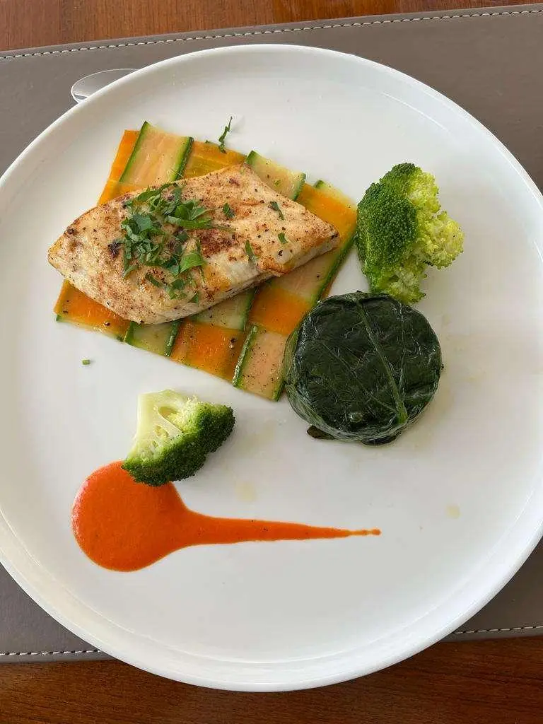 Just Marie 2 yacht menu dish plated with salmon, greens, and orange sauce