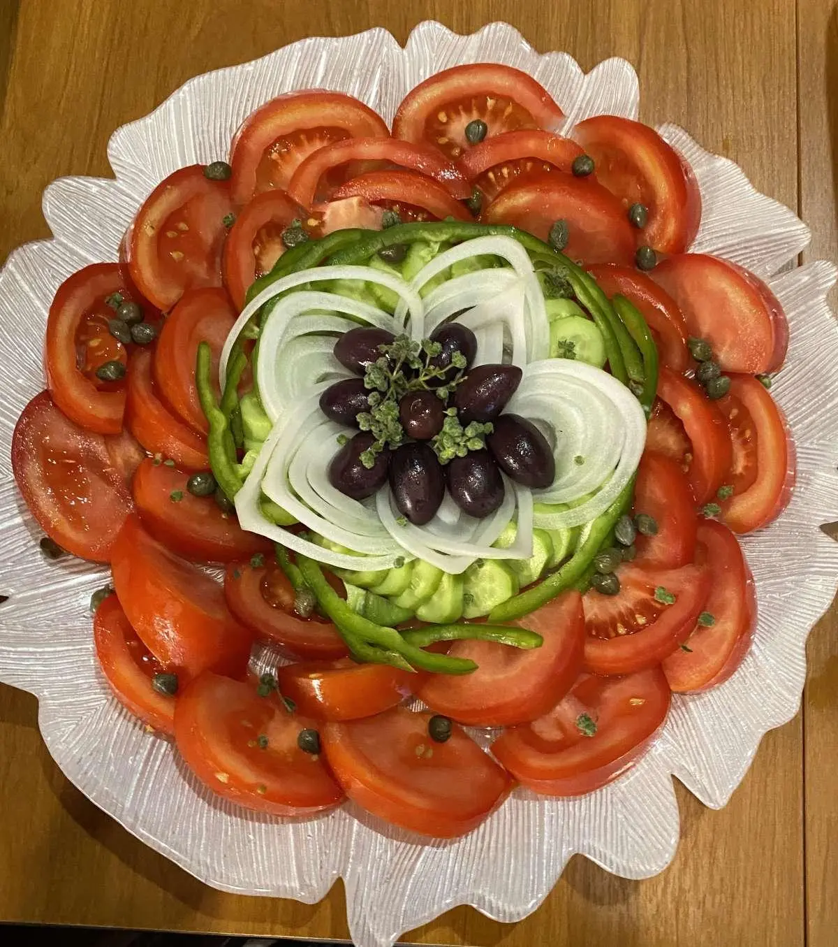 Close-up of a round plated dish with tomato slices and garnish on a white plate