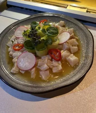 Close-up view of a plate with a colorful seafood salad and greens on a yacht table