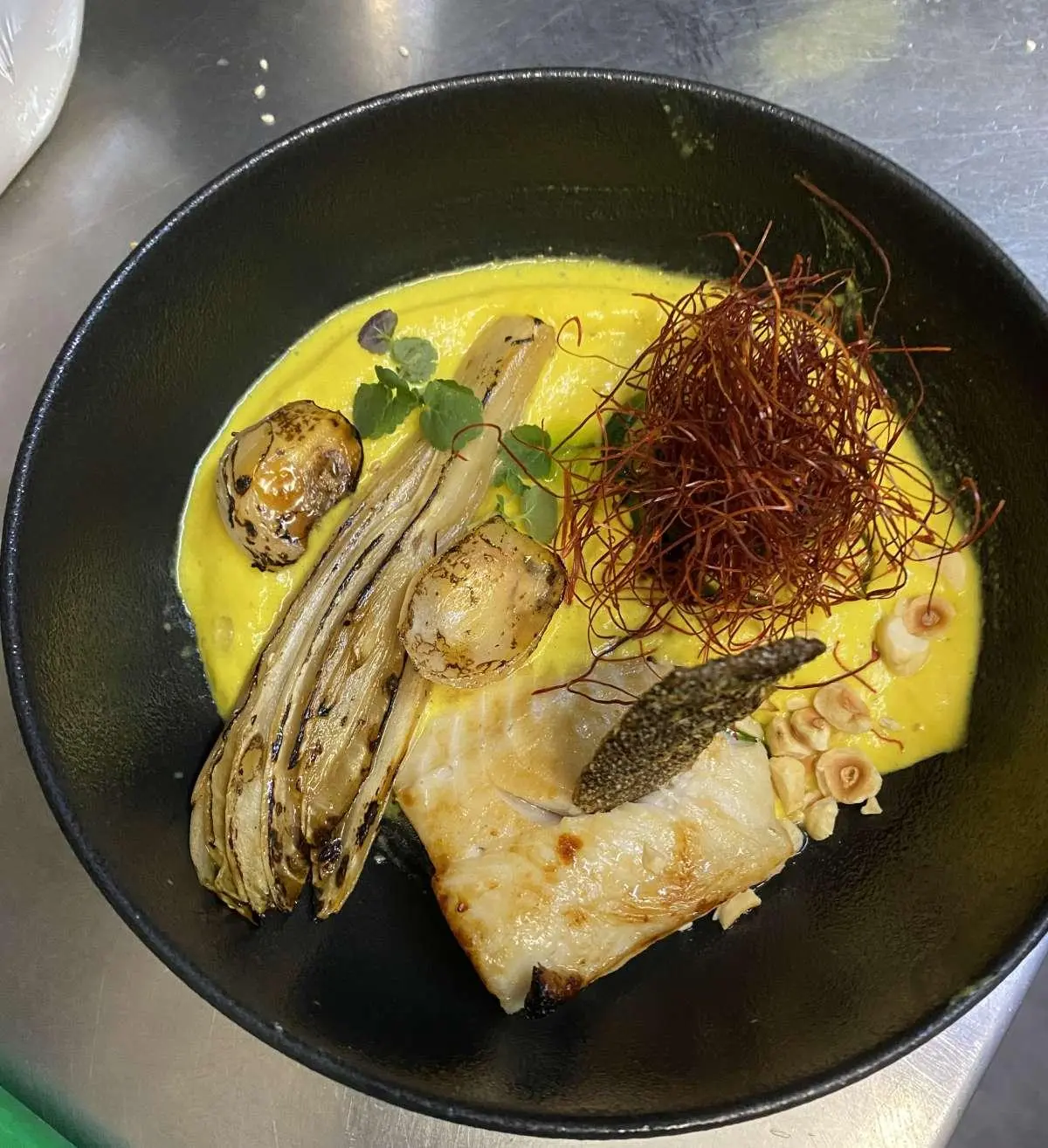 Christal Mio yacht charter image showing a dish with greens and yellow sauce in a black pan