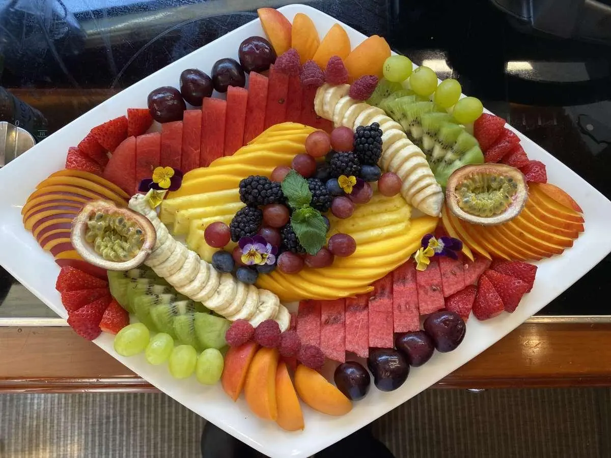 Christal Mio yacht charter image showing a fruit platter on deck with sliced fruits and grapes