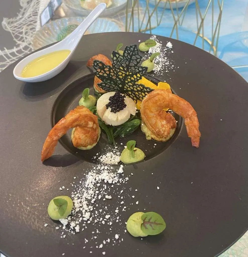 Astoria yacht charter dish on a round black plate with shrimp, lemon, greens
