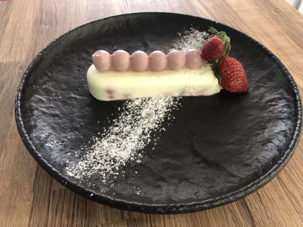 Astoria yacht menu dish on dark plate with berries and powdered sugar