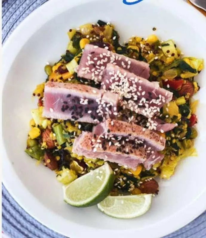 Ocean Lounge yacht passenger dining on deck with plated tuna steak and lime wedge