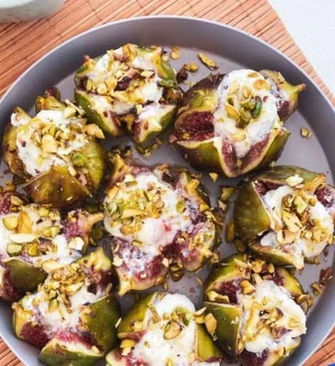 Fig and goat cheese stuffed figs with crushed pistachios on a plate