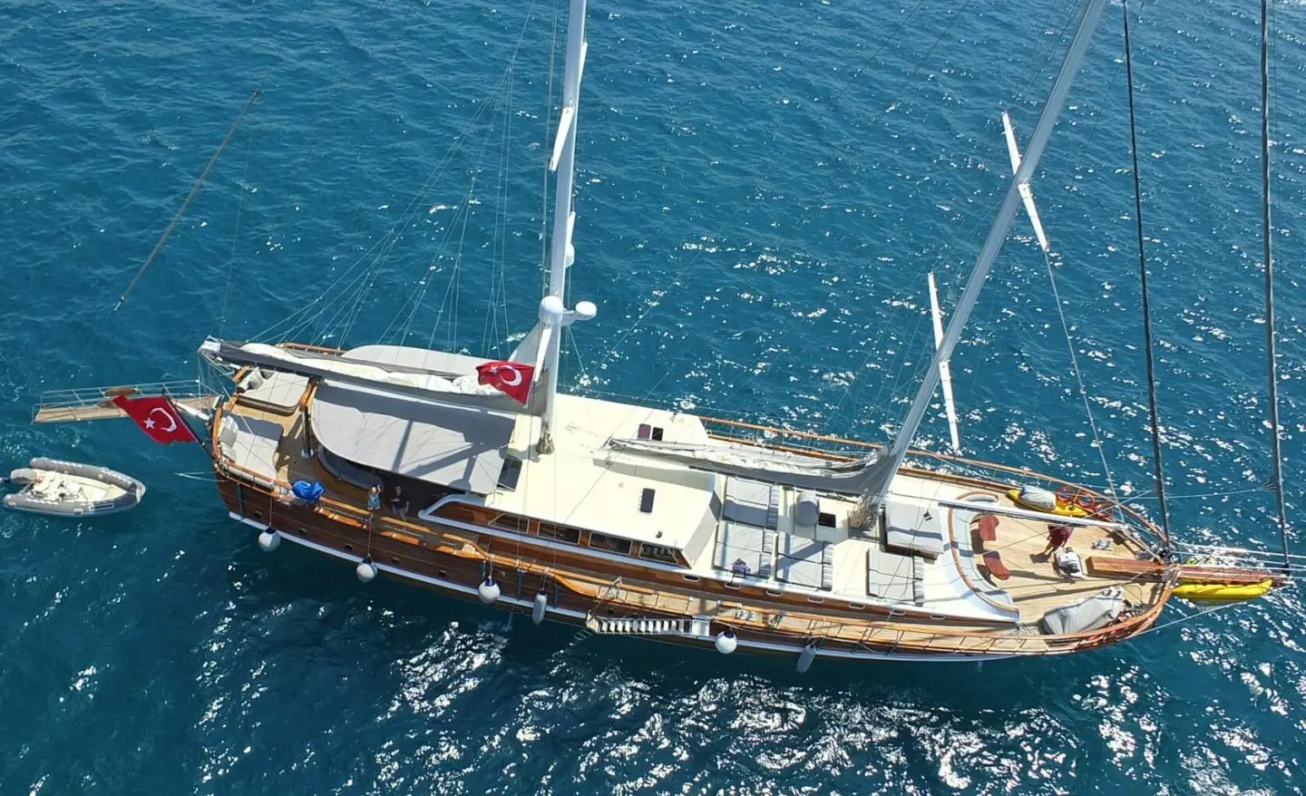 Top-down view of a luxurious gulet yacht anchored in blue sea at sunset