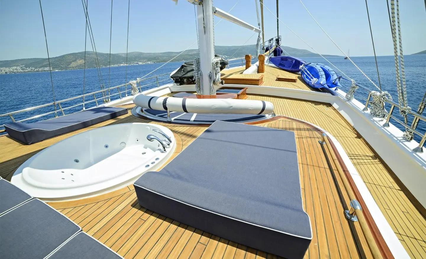 Sunlit gulet deck with wooden planks and blue cushions on an open sea