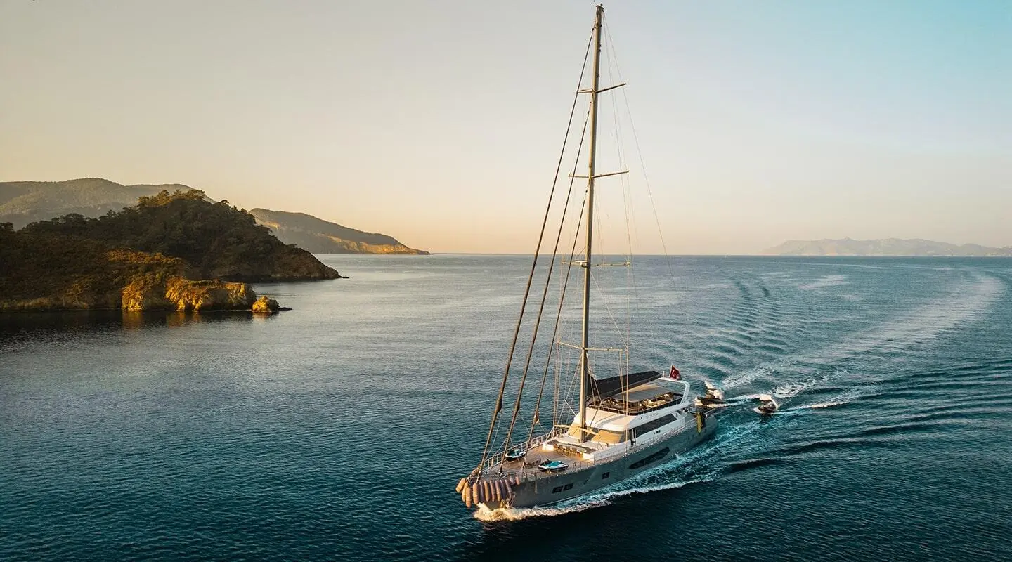 Large motor yacht sailing in calm sea near rocky coastline