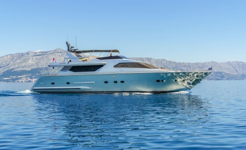 Motor yacht Phantom cruising on blue water with side view and mountains in background