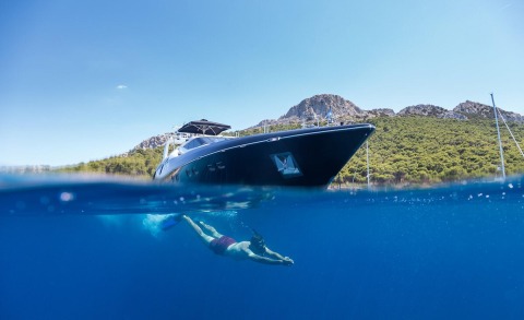 Large blue motor yacht close to the surface, visible above and below water with a swimmer underwater
