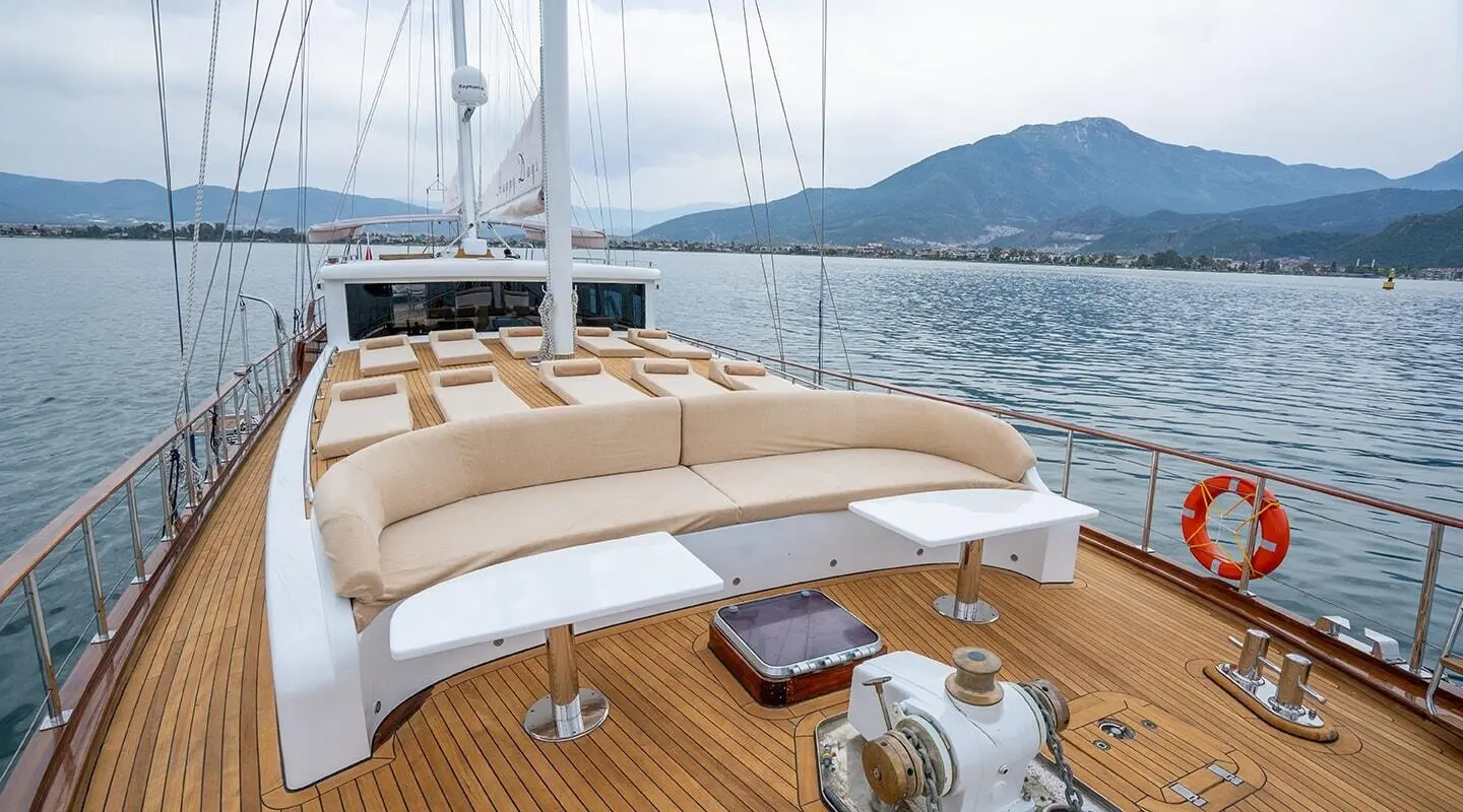 Bow deck of yacht Happy Days with beige cushioned seating and wooden deck
