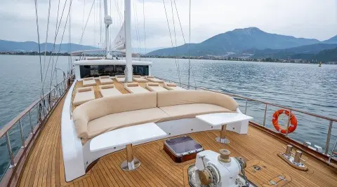 Bow deck of yacht Happy Days with beige cushioned seating and wooden deck
