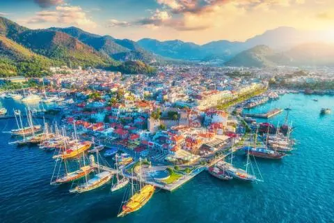 Aerial view of a marina with red-roofed buildings and blue-green water
