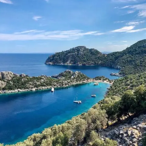 Yacht charter scene at turquoise bay with anchored boats and rocky hills