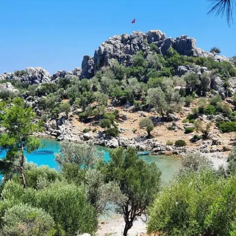 Turkish coastal cove with rocky hill, turquoise water, and pine trees