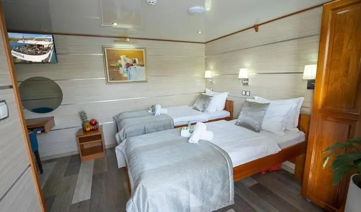 Three-bed cabin on a yacht with white bedding, beige walls and wooden accents