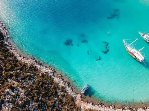 Turquoise water near rocky shoreline with a small boat in the distance