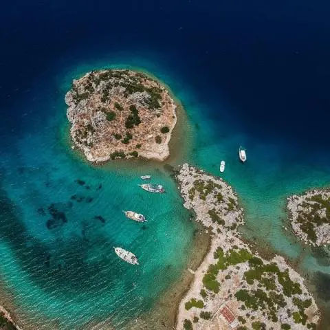 Aerial view of rocky islets in turquoise water with several moored boats nearby