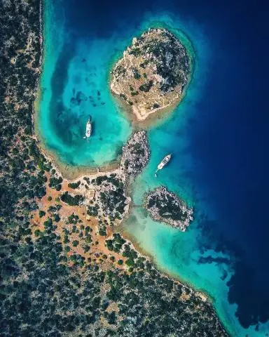 Aerial view of rocky islets and two yachts anchored in a turquoise bay