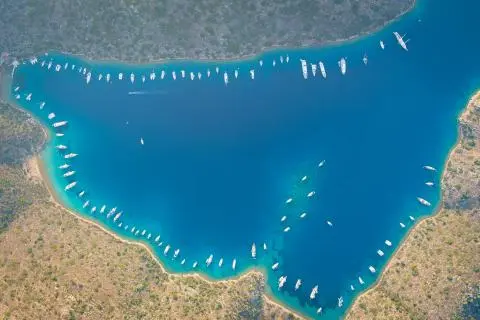 Aerial view of several yachts moored along a crescent bay shoreline