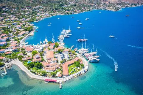 Aerial view of a marina filled with sailboats near a red-roofed coast