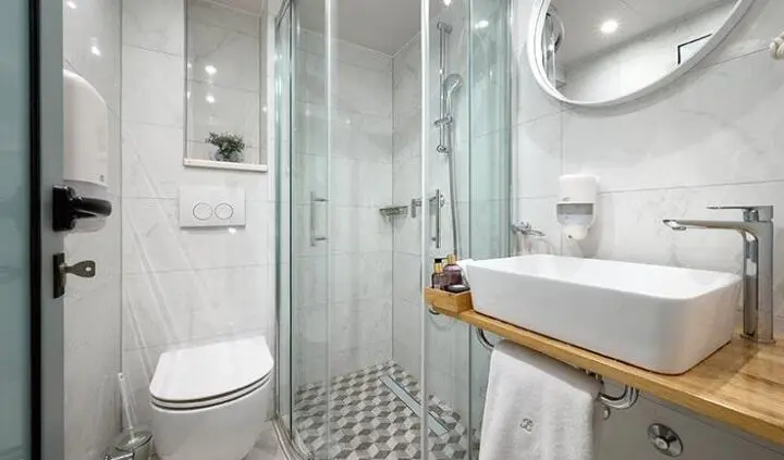 Compact yacht cabin with bed, ensuite shower, and tiled floor