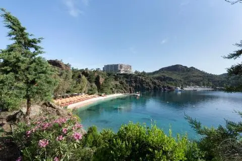 Turquoise bay with small beach, orange sunbeds, and clear water