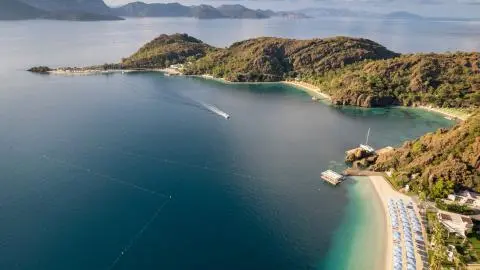 Aerial view of a sailboat near a rocky coastline with clear blue water